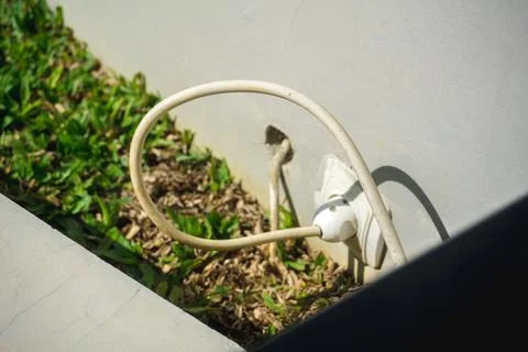 An outdoor electrical socket installed on a concrete wall with a power cabl.. Stock-Fotos