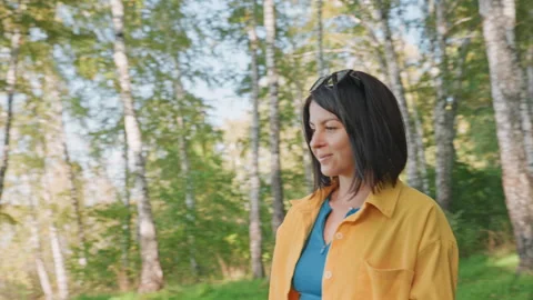 An outdoor enthusiast moves through trees towards water. Woman with outdoor Stock Footage 337828805