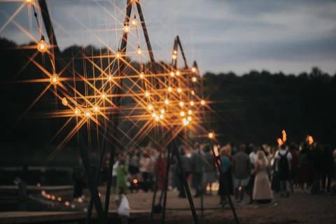 Outdoor evening gathering with decorative string lights illuminating a sand.. Stock Photos