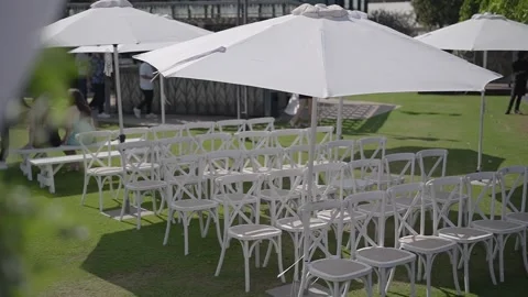 Outdoor event setup with white chairs and sun umbrellas. Stock Footage 323805051