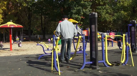 Outdoor exercise, old man working on fitness equipment in the park Stock Footage 32153183