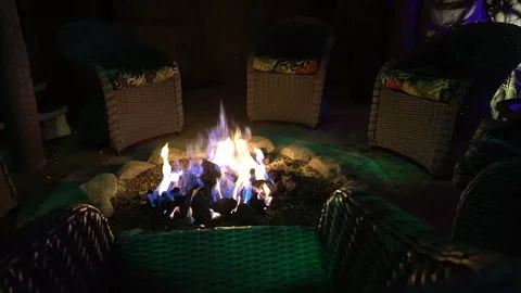 Outdoor fire pit burning among wicker chairs at night Stock Footage 345540551