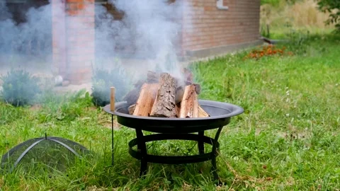 Outdoor Fire Pit Burning with Wood Flames and Smoke in Green Backyard Near Stock Footage 344814003