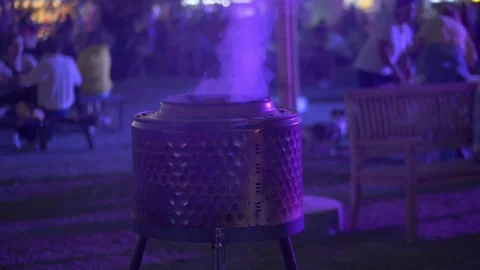 Outdoor fire pit glowing with warm light during night festival, soft purple Stock Footage 321819328