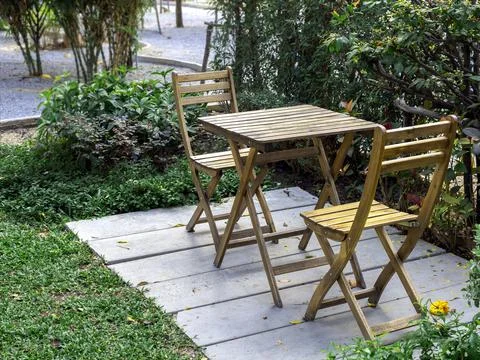 Outdoor garden table set. Empty wooden table and two chairs on concrete floor Stock Photos