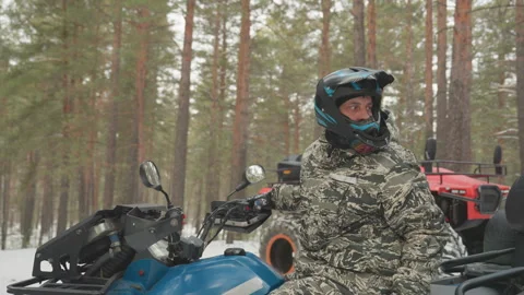 Outdoor guide inspects ATV amidst frosty pine forest readiness. Energetic rider 库存影片 332054471