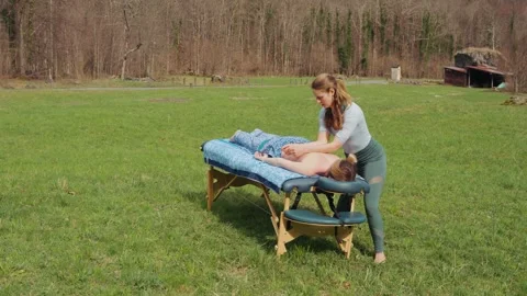 Outdoor holistic massage on a portable table in a sunny grass field, with Video stock 336744258