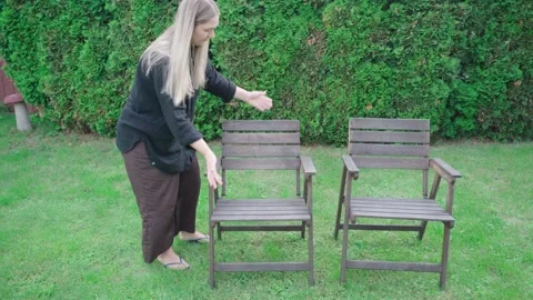 Outdoor Homeowner Testing Two Wobbly Wooden Garden Chairs for Replacement Stock Footage 340116211