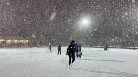 Outdoor ice rink in winter with christmas tree with big red star  in snowfall Stock Footage 120686925