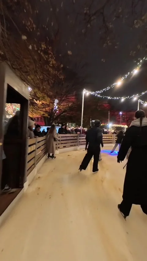Outdoor ice skating path at a Christmas market in Vienna. skaters gliding along Stock Footage 323508192