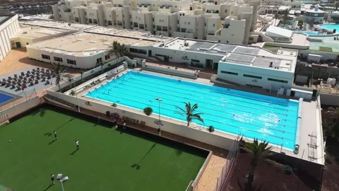Outdoor Lap Pool and Green Sports Field with Surfers and Soccer Players Stock Footage 344023186