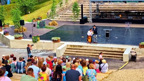 Outdoor magic performance with audience watching illusionist in interactive Stock Footage 322146259