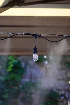 Outdoor Misting System and String Light Bulb Cooling Outdoor Cafe Patio Stock Photos