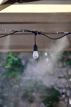 Outdoor Misting System and String Light Bulb Cooling Outdoor Cafe Patio Stock Photos