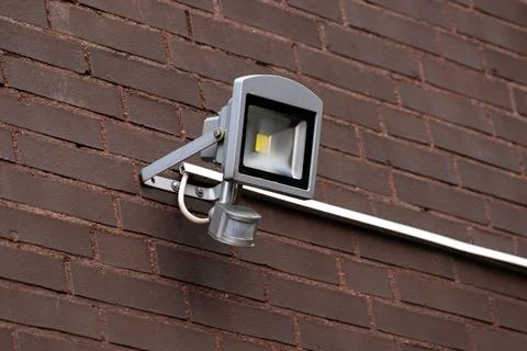Outdoor motion sensor light mounted on a brick wall near entrance Stock Photos