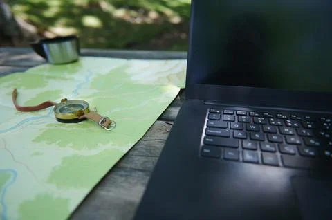 Outdoor Navigation Setup Featuring Map, Compass, and Laptop on a Wooden Table Stock Photos