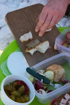 Outdoor picnic setup featuring a hand placing bacon on bread, close-up. Stock Photos