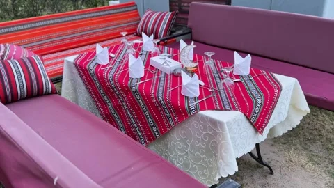 Outdoor Ramadan majlis table setup with red patterned cloth and crescent decor Stock Footage 329510011