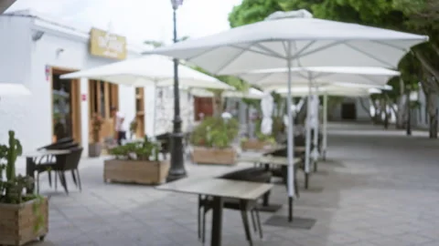 Outdoor restaurant with empty tables and chairs under umbrellas in a blurre.. Stock Footage 289327129