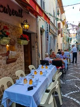 Outdoor restaurant table set for dinner in narrow alley of Antibes old town Stock Photos