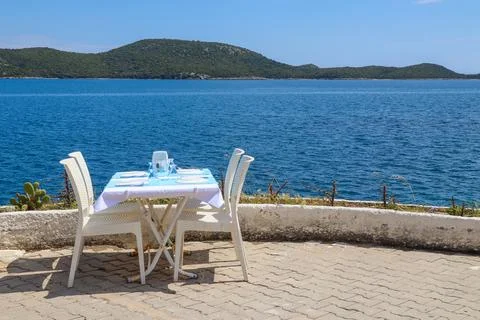 Outdoor restaurant table setting overlooking the beautiful blue Aegean Sea .. 库存照片