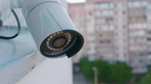 Outdoor Security Camera Mounted on Building Wall with Blurred City Background Stock Footage 338100984