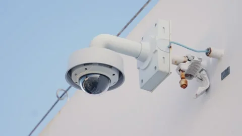 Outdoor security dome camera mounted on white industrial metal wall Stock Footage 342061504