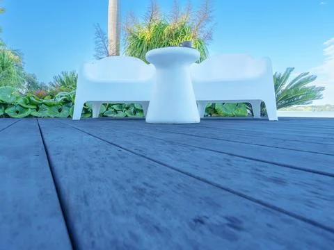 Outdoor setting two chairs and small table on deck with greenery background Stock Photos