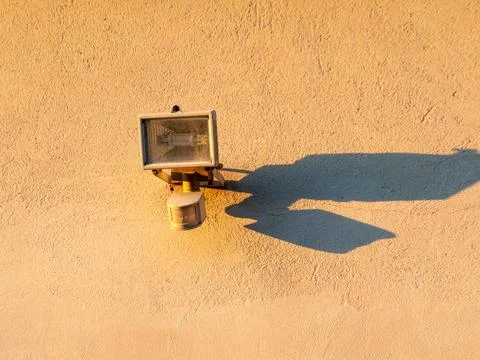 Outdoor spotlight casts sharp shadow on textured wall Stock Photos