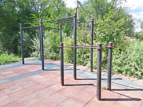 Outdoor street workout ground with pull-up bars and parallel bars in a green par Stock Photos
