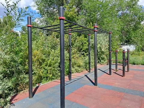 Outdoor street workout ground with pull-up bars and parallel bars in a green par Stock Photos