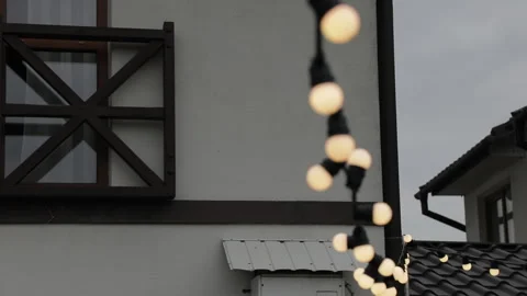 Outdoor string lights decorating a courtyard between buildings adorned with dark Stock Footage 322558204