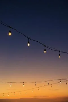 Outdoor String Lights Glowing Against a Vibrant Tropical Sunset Sky Stock Photos