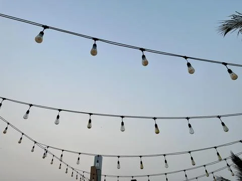 Outdoor String Lights Hanging Against Clear Evening Sky Background at Café Venue Stock Photos