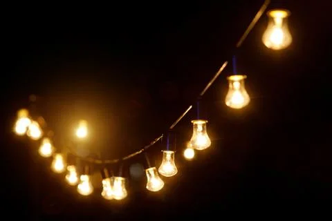 Outdoor string lights hanging on a line in backyard. Stock Photos
