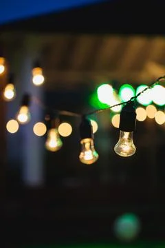 Outdoor string lights hanging on a line in backyard. Stock Photos