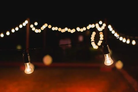 Outdoor string lights hanging on a line in backyard. Stock Photos