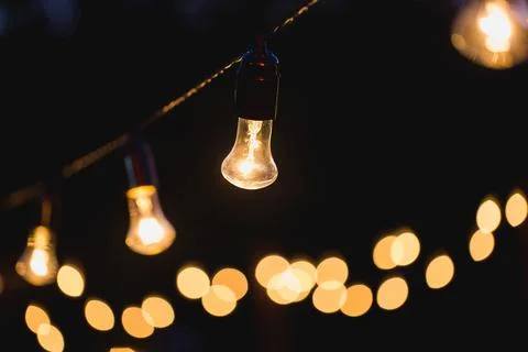 Outdoor string lights hanging on a line in backyard. Stock Photos