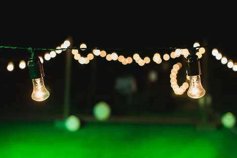 Outdoor string lights hanging on a line in backyard. Stock Photos