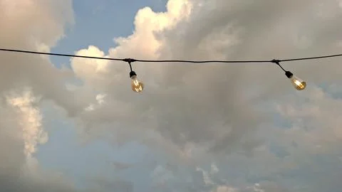 Outdoor String Lights Hanging Under Cloudy Sunset Sky Stock Photos