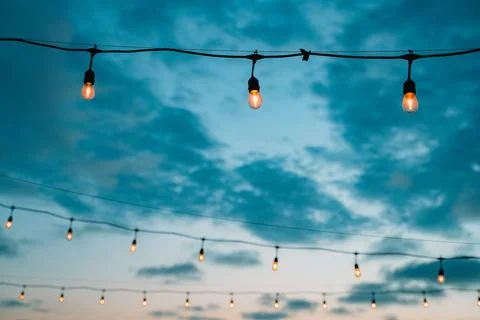 Outdoor string lights in sunset sky Stock Photos