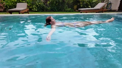 Outdoor swimming pool back float relaxing woman wearing swimsuit hotel villa Video stock 312232029