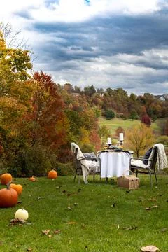 Outdoor table setting for two in a dramatic fall background with pumpkins lining Stock Photos