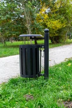 Outdoor trash bin with attached table situated along a walking path in a park Stock Photos