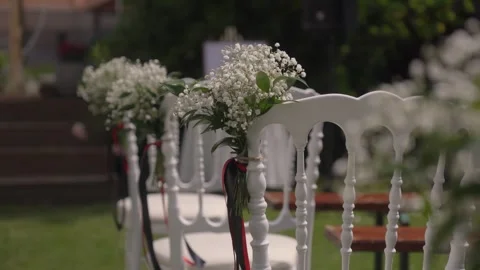 Outdoor Wedding Ceremony Setup With White Chairs and Floral Decorations in Stock Footage 342279519