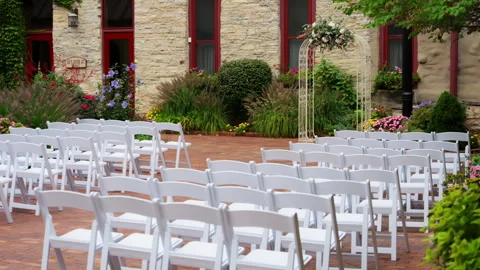 Outdoor wedding setup with rows of white chairs . The setting is on a yard Stock-Footage 311749710