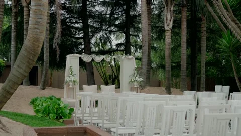 Outdoor wedding setup with white chairs and an elegant altar in a tropical Stock Footage 282514462
