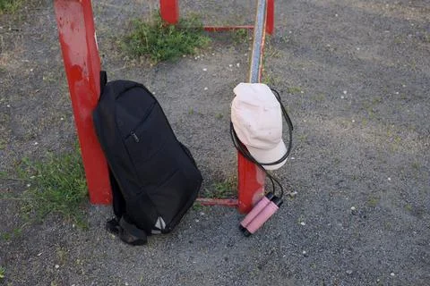 Outdoor workout gear: backpack, cap, and jump rope resting on gym equipment Stock Photos