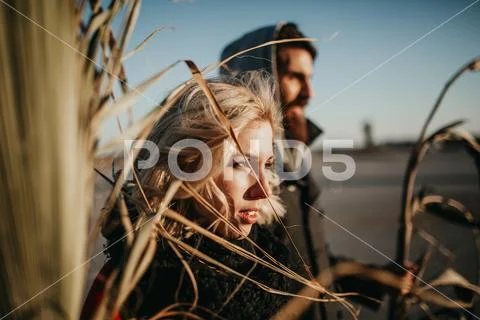 Outdoors blonde woman portrait and boyfriend in the background. Stock Photos