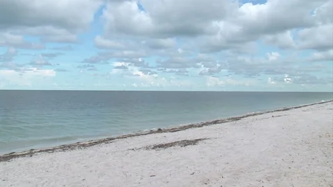 Outdoors-empty beach-ocean-gentle waves-sand-blue sky-puffy clouds-outdoors Video stock 153050124